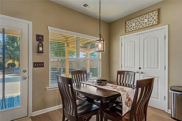 a kitchen with stainless steel appliances granite countertop a dining table chairs refrigerator and microwave