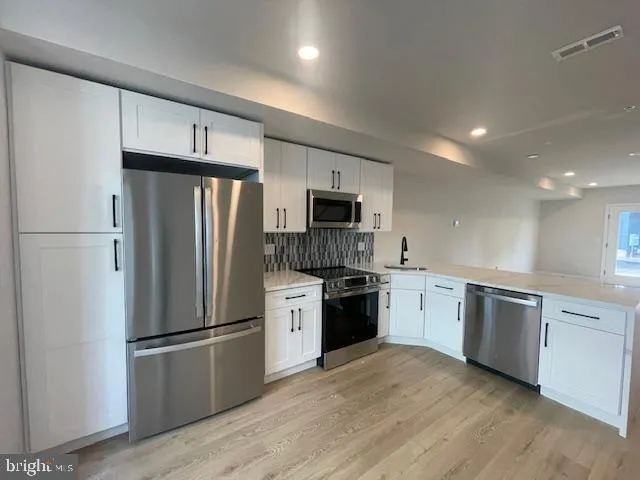 a kitchen with stainless steel appliances a refrigerator stove microwave and sink