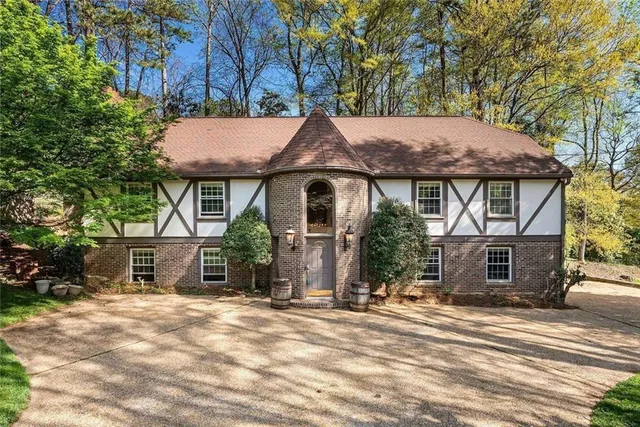a front view of a house with a garden and trees