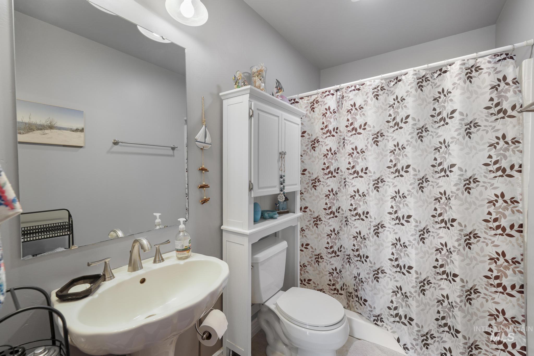 467 Wildrose Loop Twin Falls, ID 83301 - Photo 33 of 46 Pedestal sink with brushed nickel faucet, large wall mirror, and a built-in over-toilet storage cabinet