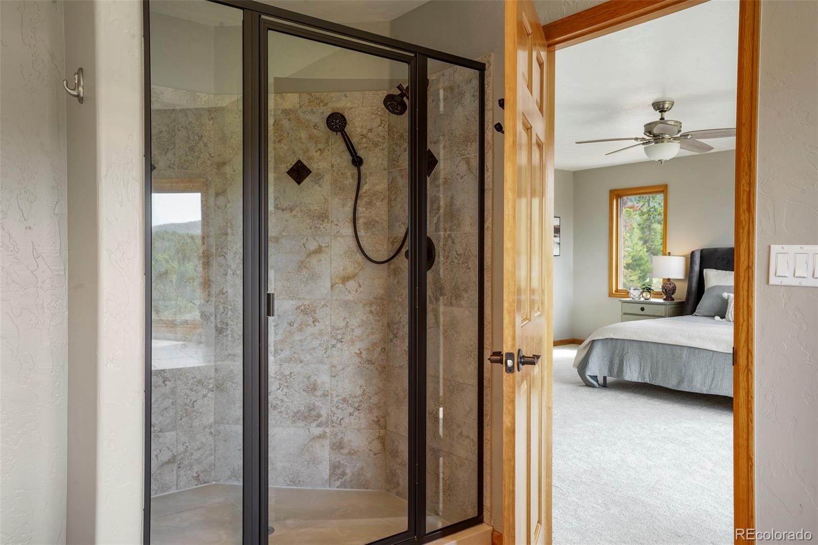 29549 Thunderbolt Circle Conifer, CO 80433 - Photo 17 of 50 a en suite bathroom with a glass shower door and a mirror