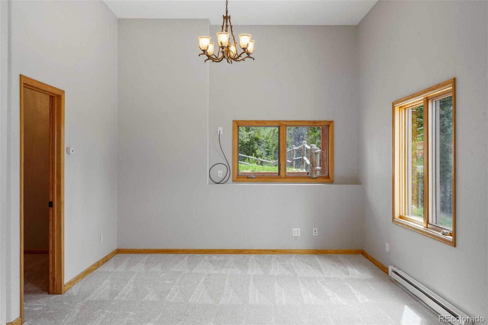 29549 Thunderbolt Circle Conifer, CO 80433 - Photo 27 of 50 an empty room with windows and chandelier