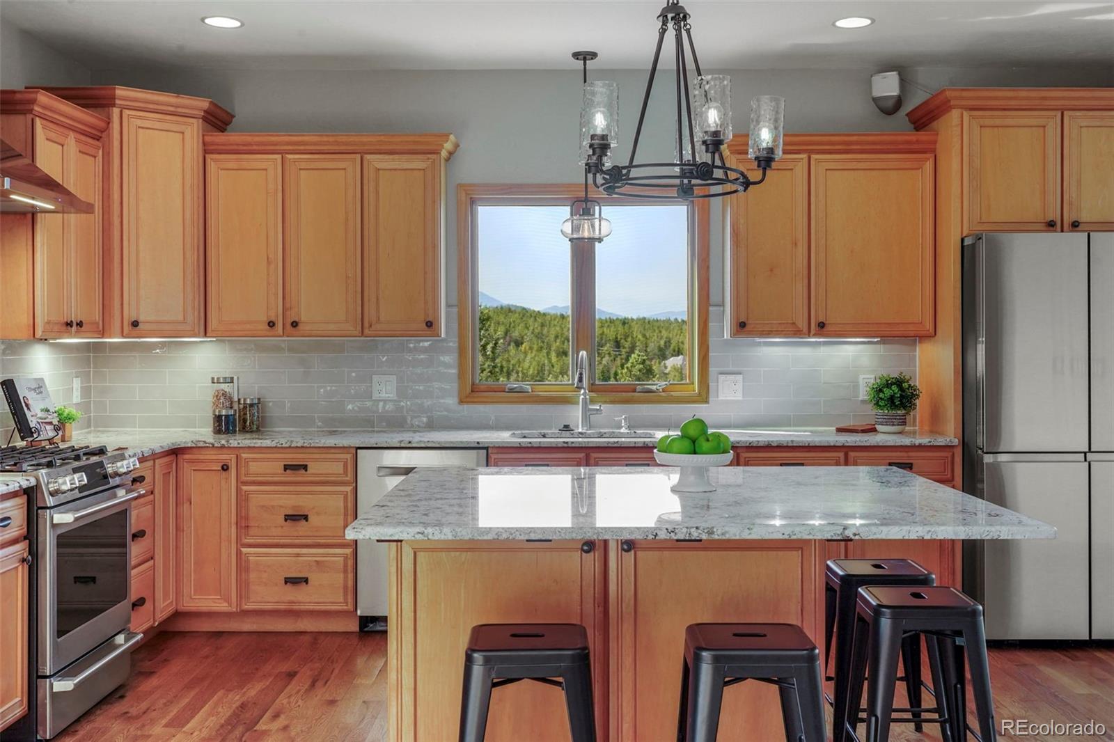 29549 Thunderbolt Circle Conifer, CO 80433 - Photo 7 of 50 a kitchen with kitchen island granite countertop a stove a sink dishwasher and wooden cabinets with wooden floor