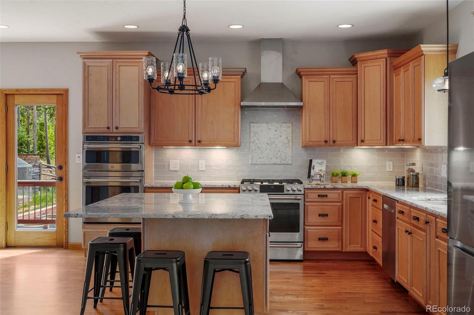 29549 Thunderbolt Circle Conifer, CO 80433 - Photo 9 of 50 a kitchen with kitchen island granite countertop wooden cabinets stainless steel appliances and a counter top space
