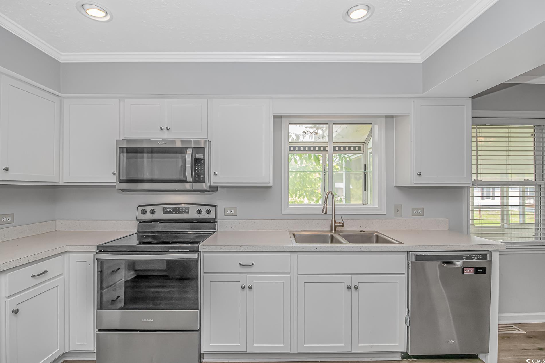2829 Highway 129 Galivants Ferry, SC 29544 - Photo 7 of 40 Kitchen featuring stainless steel appliances, white cabinetry, light countertops, recessed lighting, and crown molding