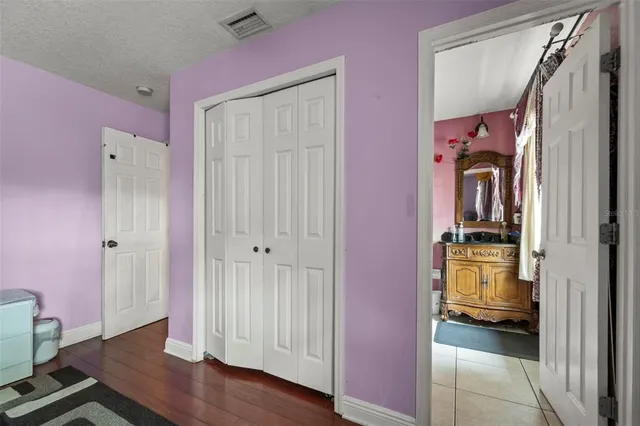 a view of a hallway with wooden floor and a bathroom