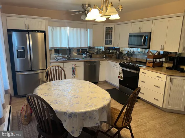 a kitchen with stainless steel appliances granite countertop a refrigerator a stove a sink dishwasher a dining table and chairs with wooden floor