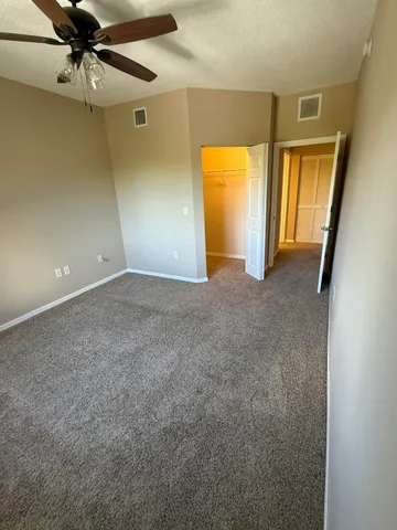 an empty room with a mirror and a ceiling fan