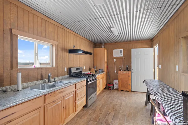 a large kitchen with a large window a sink and cabinets
