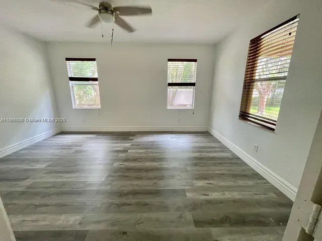 a view of an empty room with a window and wooden floor