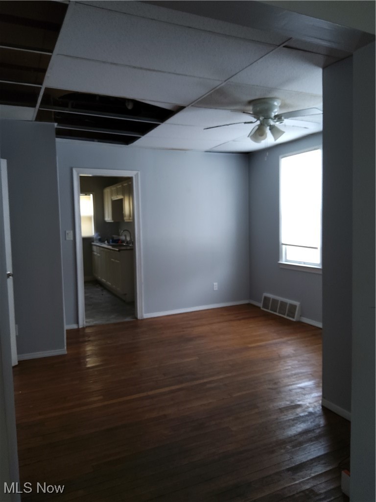 7117 Ottawa Road Cleveland, OH 44105 - Photo 7 of 25 Empty room featuring dark wood-type flooring, ceiling fan, and a paneled ceiling