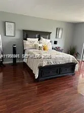 a large bed sitting in a bedroom next to a window with wooden floor