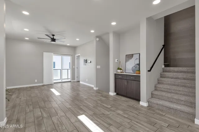 a view of an empty room with wooden floor and a ceiling fan