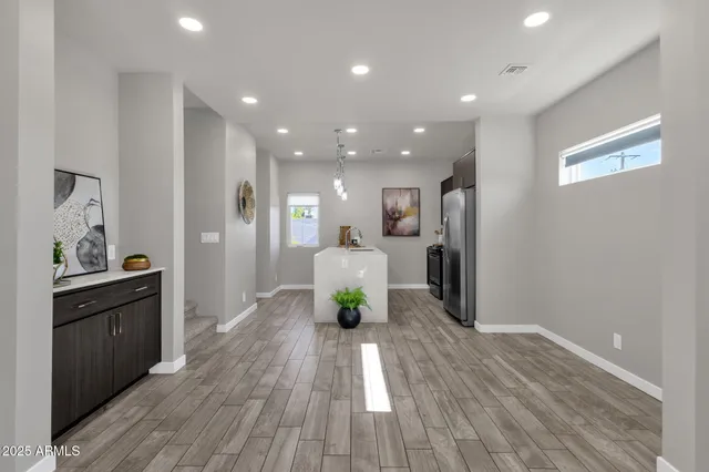 a living room with stainless steel appliances furniture refrigerator and wooden floor