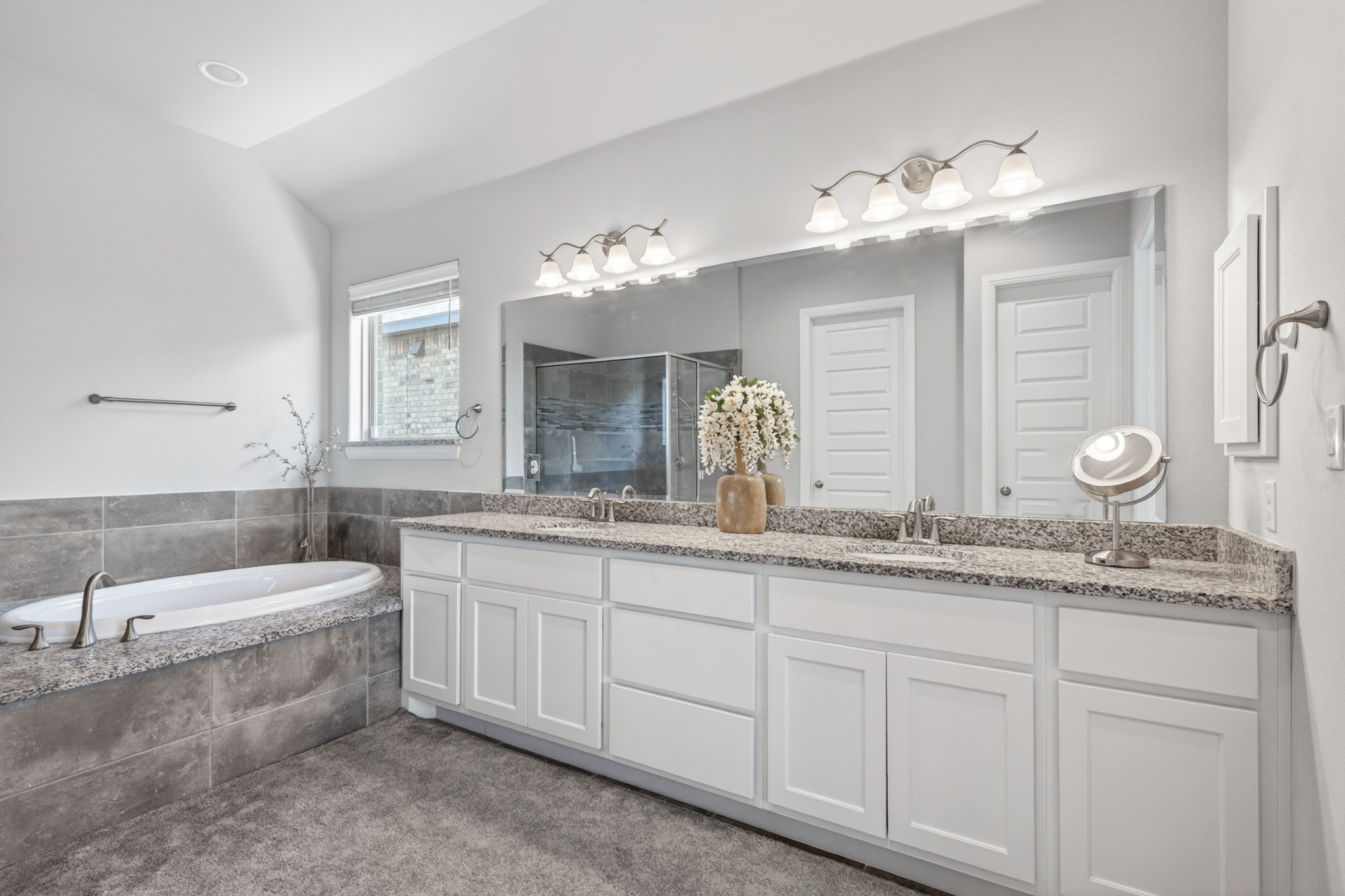 4105 Haight Street Round Rock, TX 78681 - Photo 21 of 40 a bathroom with a double vanity sink a large mirror a bathtub and shower