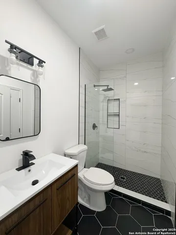 a bathroom with a toilet a sink a mirror and shower