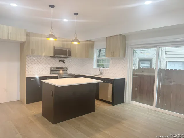 a kitchen with kitchen island a counter top space a sink stainless steel appliances and cabinets