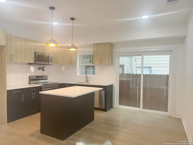 a kitchen with stainless steel appliances granite countertop a sink a stove and a refrigerator