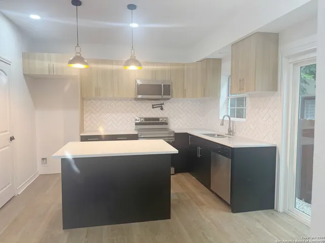 a kitchen with kitchen island a sink stainless steel appliances and cabinets
