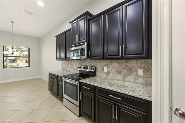 a large kitchen with granite countertop a large counter top stainless steel appliances and cabinets