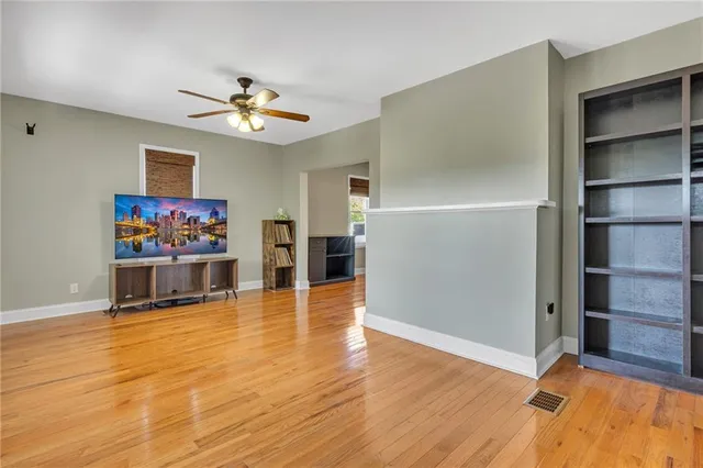 a view of an empty room with a window and wooden floor