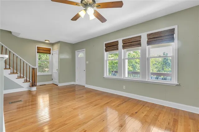 a view of an empty room with wooden floor and a window