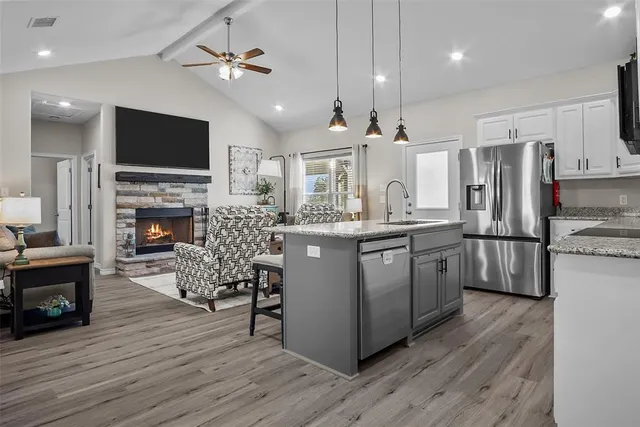 a kitchen with stainless steel appliances granite countertop a refrigerator a stove a sink dishwasher a dining table and chairs with wooden floor