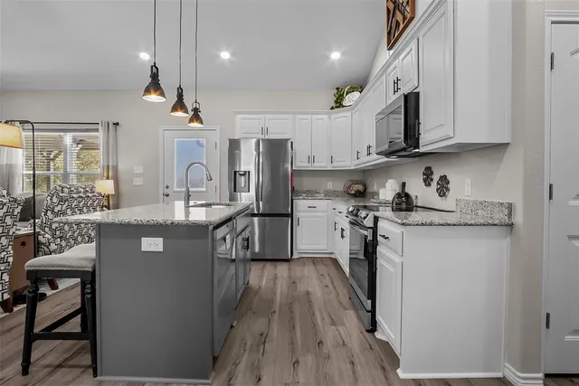 a kitchen with stainless steel appliances granite countertop a sink refrigerator and cabinets