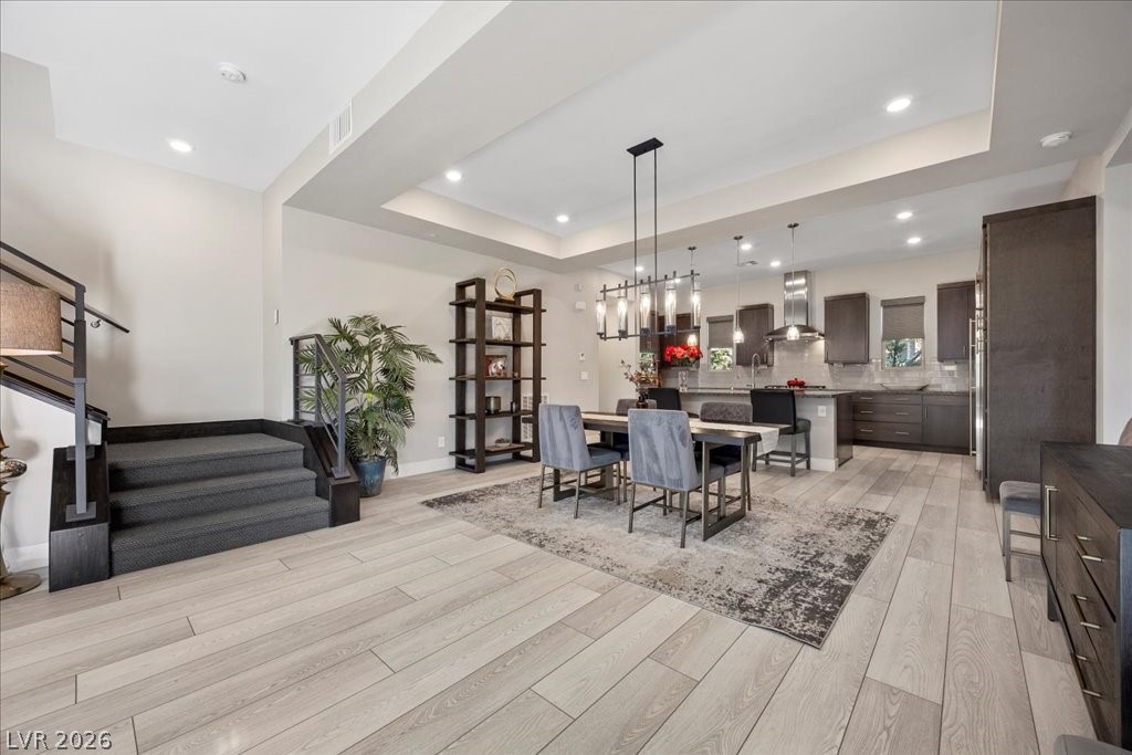 4262 Swift Street Las Vegas, NV 89135 - Photo 13 of 75 Dining space with a raised ceiling, recessed lighting, light wood-style flooring, and stairs