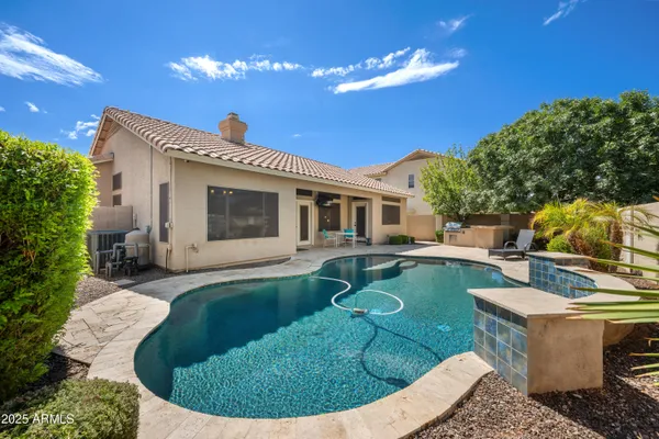 a view of a patio with table and chairs near a barbeque