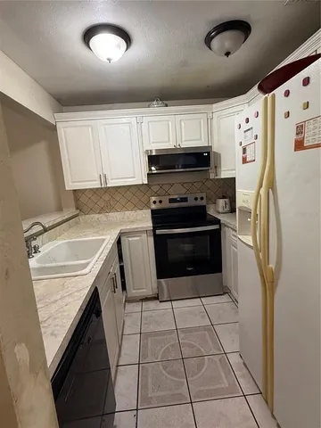 a kitchen with granite countertop a refrigerator sink stove and cabinets