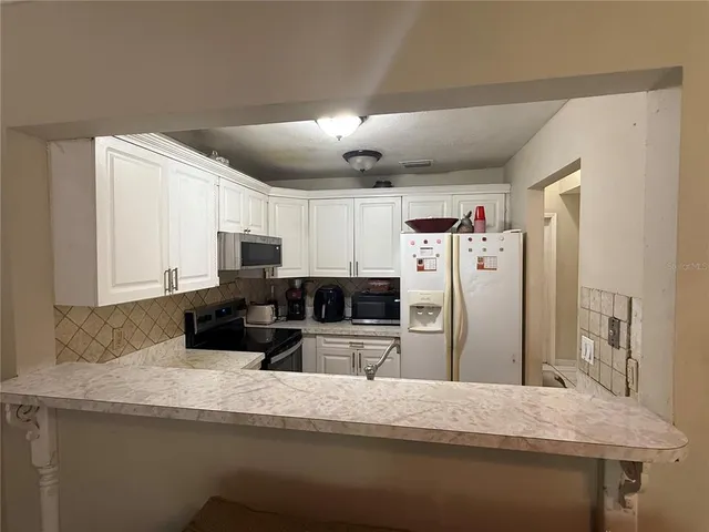 a kitchen with stainless steel appliances granite countertop a refrigerator a stove and a sink