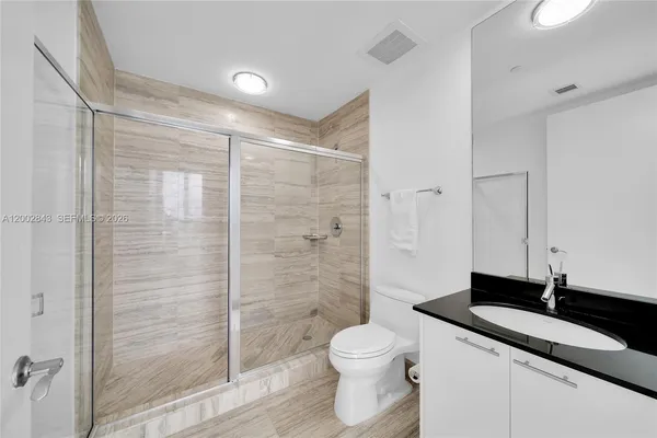 a bathroom with a granite countertop sink a toilet and shower