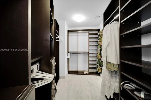a view of walk in closet with clothes and shoes
