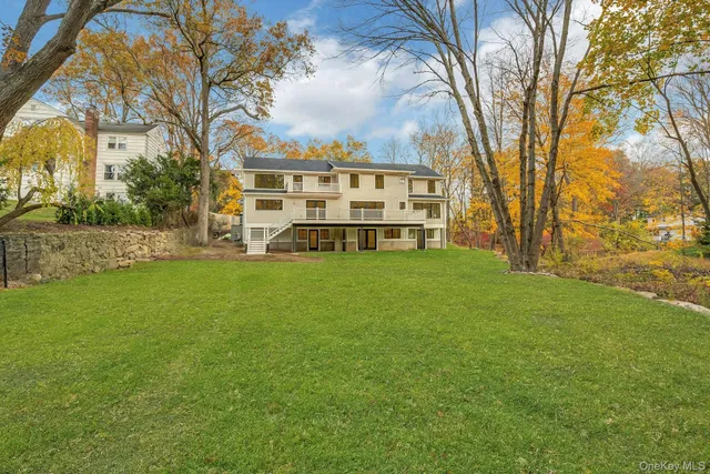a view of a house with a big yard and large trees