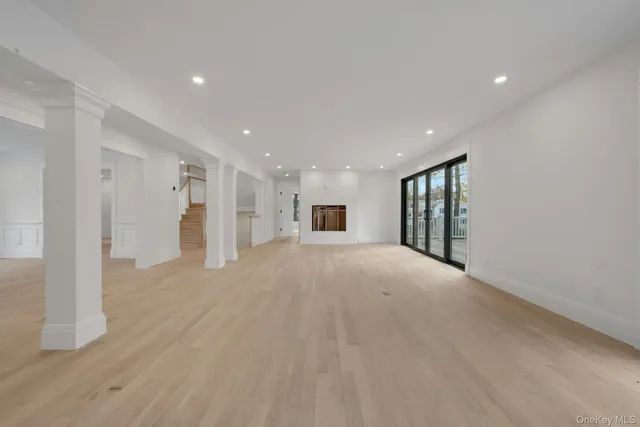 a view of an empty room with wooden floor and windows