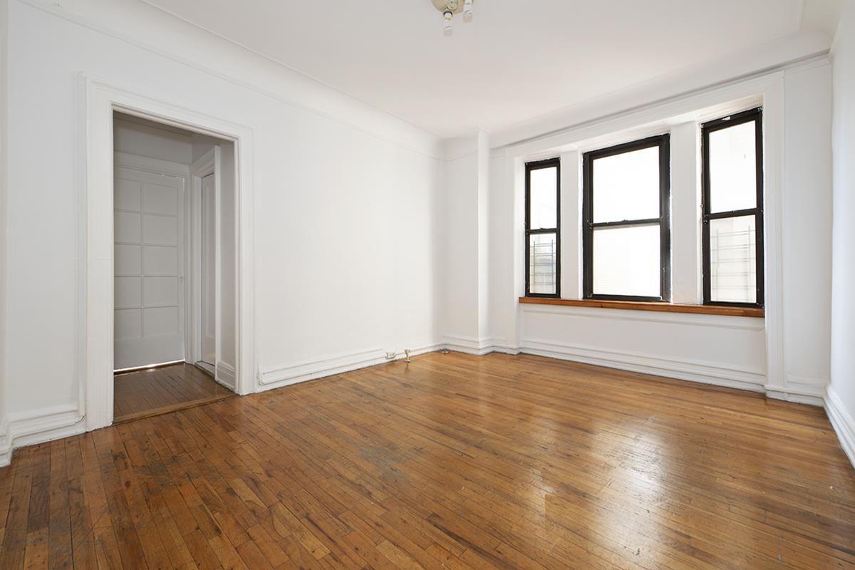 409 Edgecombe Avenue, Unit 1D Manhattan, NY 10032 - Photo 4 of 8 a view of an empty room with wooden floor and a window
