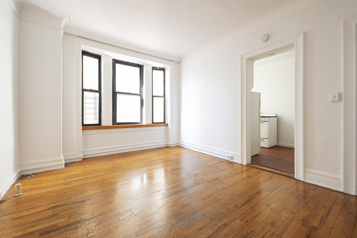 409 Edgecombe Avenue, Unit 1D Manhattan, NY 10032 - Photo 5 of 8 a view of an empty room with wooden floor and a window