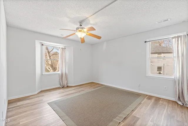 an empty room with windows and chandelier fan