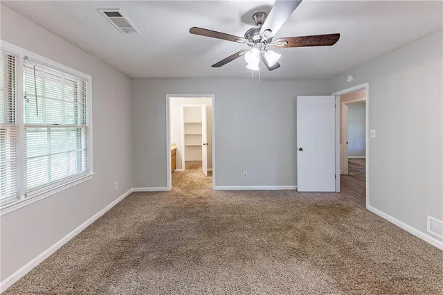 an empty room with windows and fan
