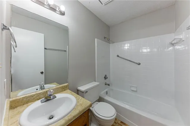 a bathroom with a bathtub shower sink vanity mirror and toilet