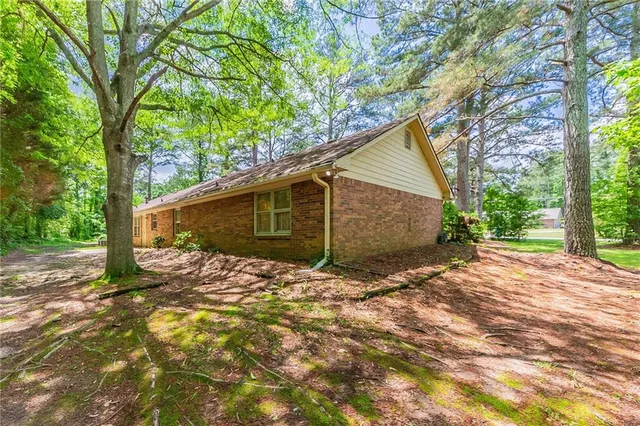 a backyard of a house with large trees and plants