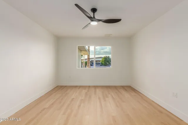 an empty room with a window and a ceiling fan