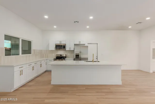 a large white kitchen with cabinets and wooden floor
