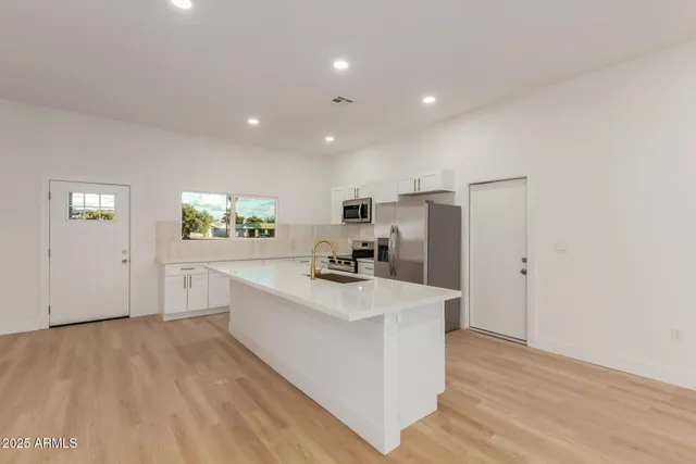a large kitchen with a center island wooden floor and stainless steel appliances