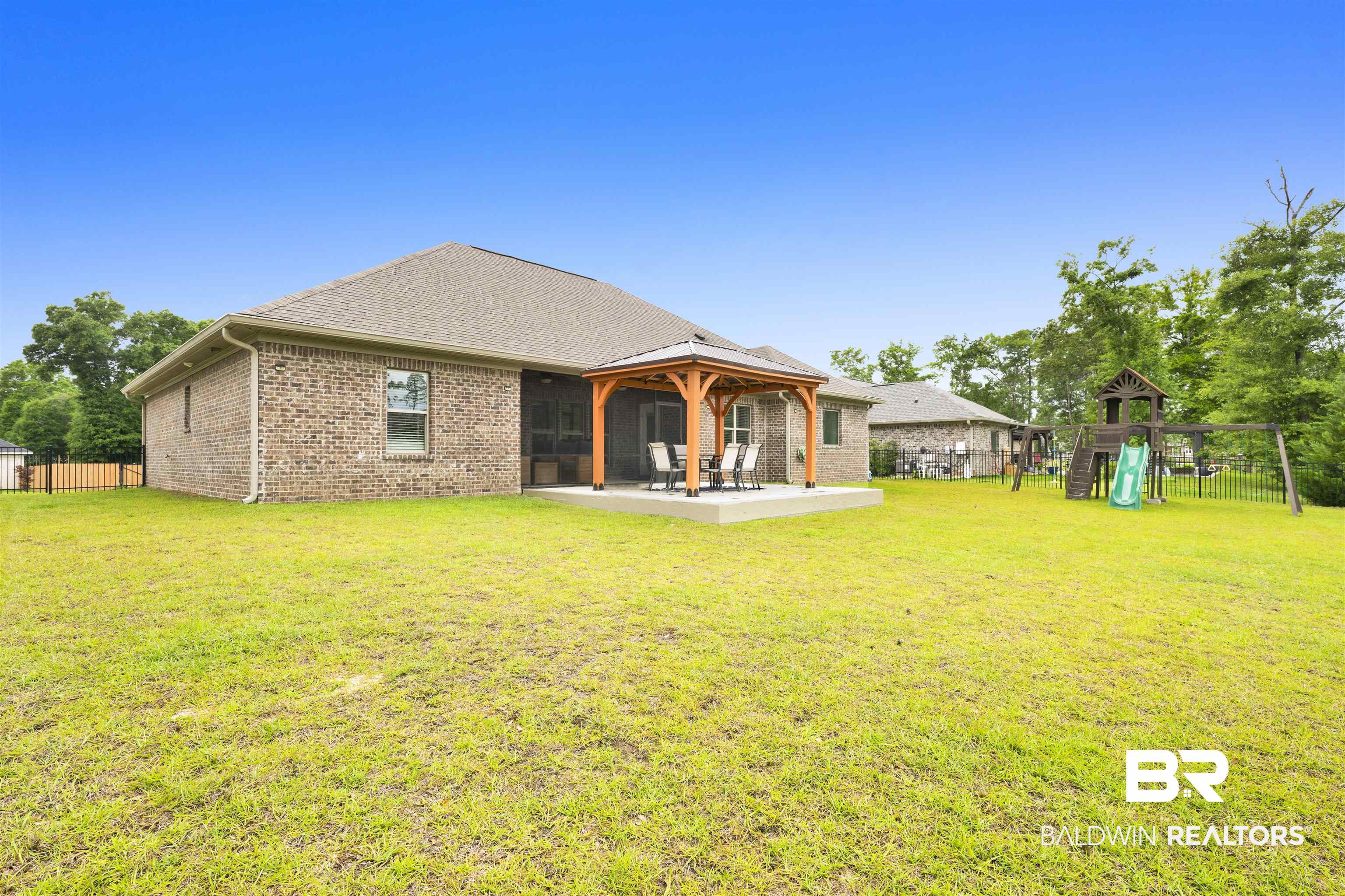 12672 Squirrel Drive Daphne, AL 36527 - Photo 39 of 49 Expansive backyard featuring a covered patio with a wooden pergola, a concrete patio, and mature trees beyond the property line