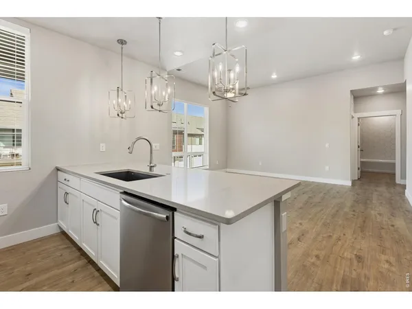 a kitchen with a sink chandelier and wooden floor