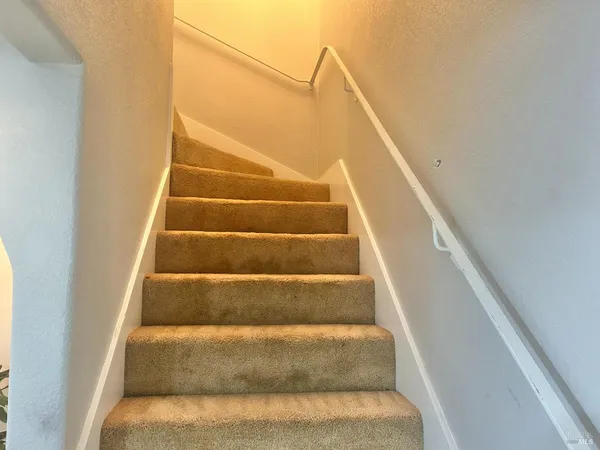 a view of staircase with white walls and white door