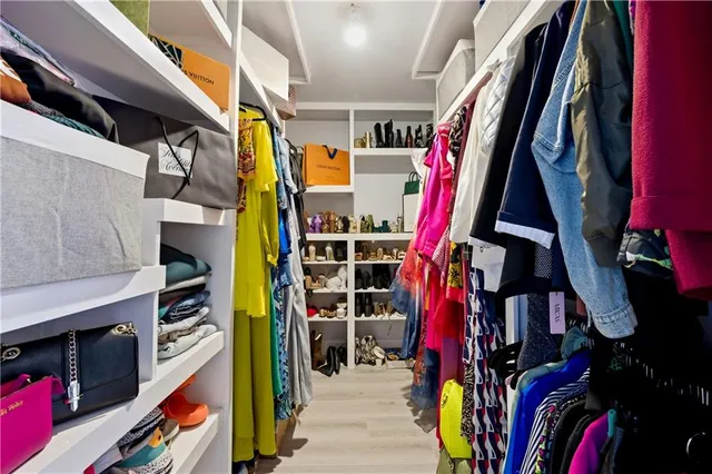 a view of walk in closet with clothes and shoes