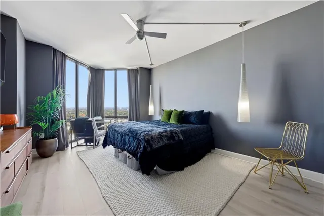 a bedroom with a bed a chair and potted plant on the dresser